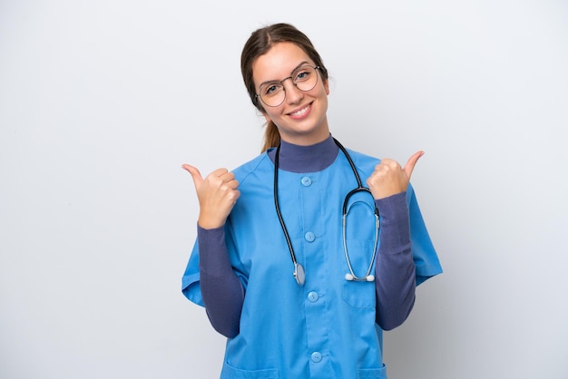 Jovem enfermeira caucasiana isolada em fundo branco com polegares para cima gesto e sorrindo
