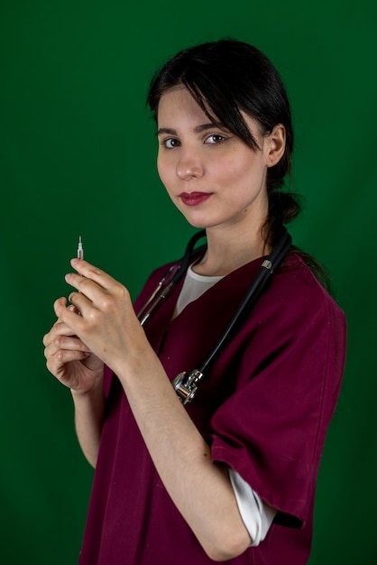 Jovem enfermeira feminina segura uma seringa com uma agulha na mão em roupas médicas isoladas