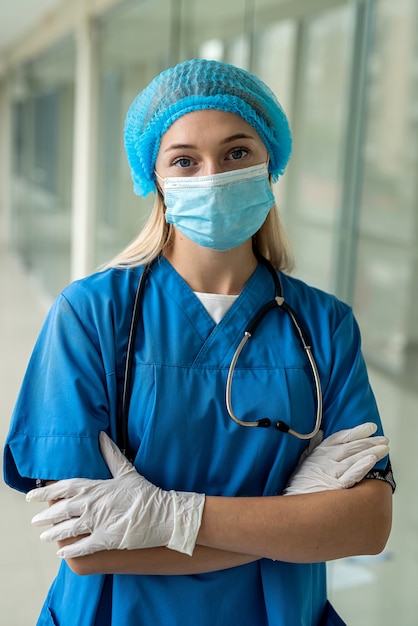 Jovem enfermeira linda no corredor com luvas de máscara uniforme. Conceito de medicina