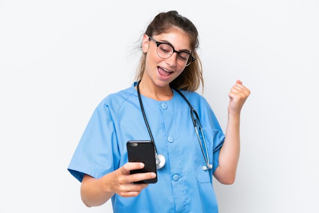 Jovem enfermeira médica isolada em fundo branco com telefone na posição de vitória