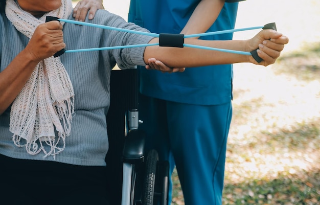 Jovem enfermeira ou fisioterapeuta ajudando uma velha feliz aposentada a fazer exercícios físicos com halteres leves em casa Conceito de fisioterapia para idosos