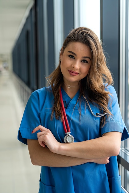 Jovem enfermeira sexy ou médica femele de uniforme azul posando no moderno corredor de saúde clínica