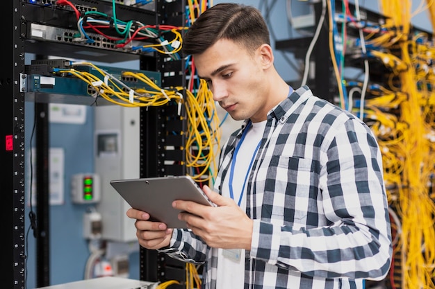 Foto jovem engenheiro com um tablet na sala do servidor tiro médio