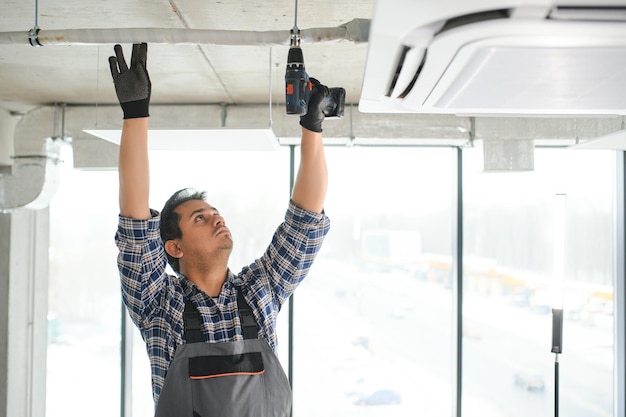 Jovem engenheiro indiano concentrado a instalar ar condicionado