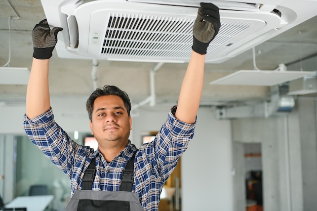 Jovem engenheiro indiano concentrado a montar ar condicionado
