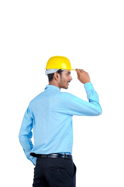 Jovem engenheiro indiano do sexo masculino usando capacete de cor amarela sobre fundo branco.