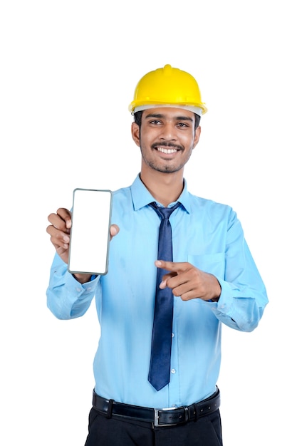 Jovem engenheiro indiano ou trabalhador da construção civil mostrando a tela do smartphone.