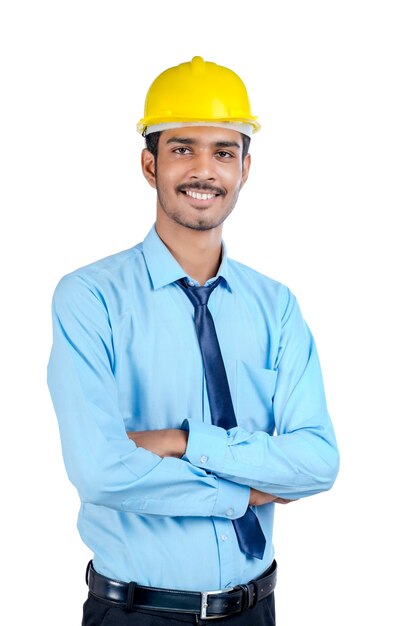Jovem engenheiro indiano usando capacete de cor amarela e fazendo um gesto de sucesso.