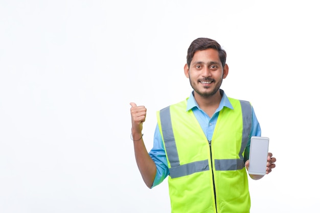 Jovem engenheiro mostrando a tela do smartphone em fundo branco.