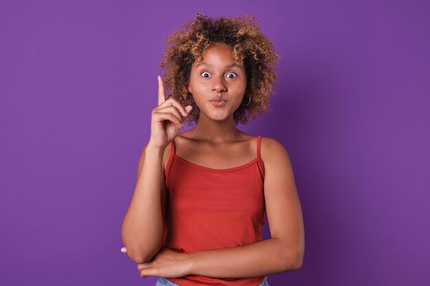 Foto jovem engraçada mulher afro-americana adolescente apontando com o dedo para cima está no estúdio