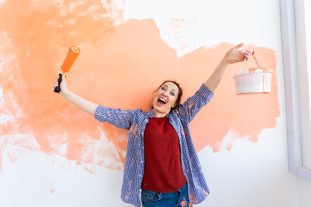 Foto jovem engraçada pintando a parede em seu novo apartamento