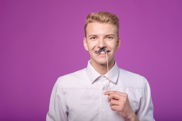 Jovem engraçado com bigode de papel no fundo