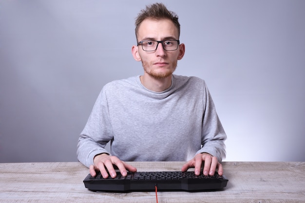 Jovem engraçado nerd trabalhando no computador. digitando no programador de teclado em copos na frente do computador.