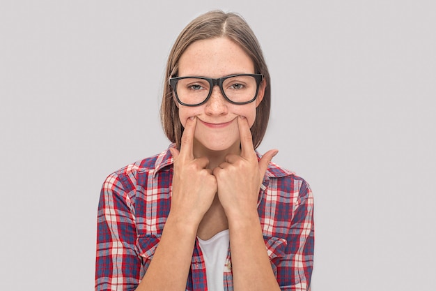 Jovem entediada mas engraçada coloca os dedos em seus sorrisos.