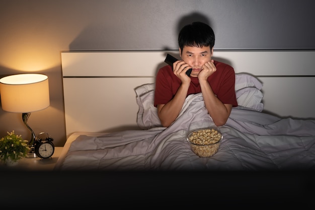 Jovem entediado assistindo TV na cama à noite