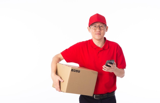 Jovem entregador asiático de uniforme vermelho carrega caixa de papelão nas mãos isoladas em fundo branco