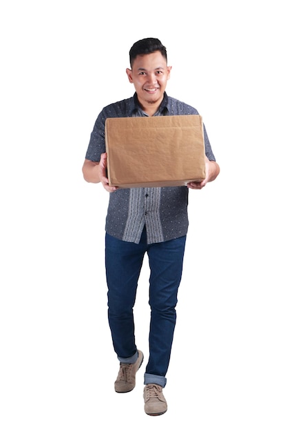 Jovem entregador asiático vestindo camisa batik sorrindo e carregando uma caixa de pacote