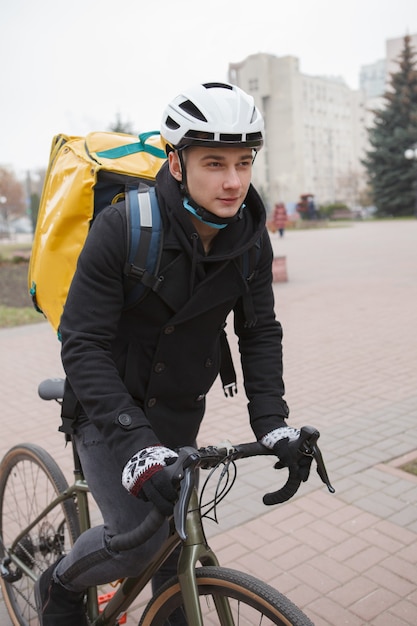 Jovem entregador com mochila térmica andando de bicicleta