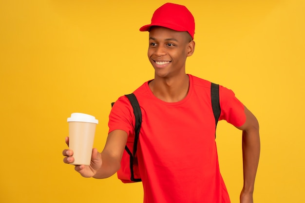 Jovem entregador segurando uma xícara de café para viagem.