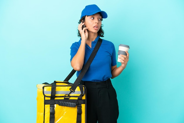 Jovem entregadora com mochila térmica segurando café para levar e um celular
