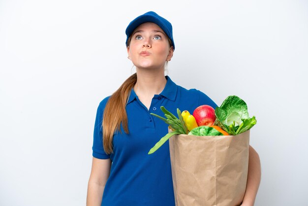Foto jovem entregadora levando um saco de comida para viagem isolada no fundo branco e olhando para cima