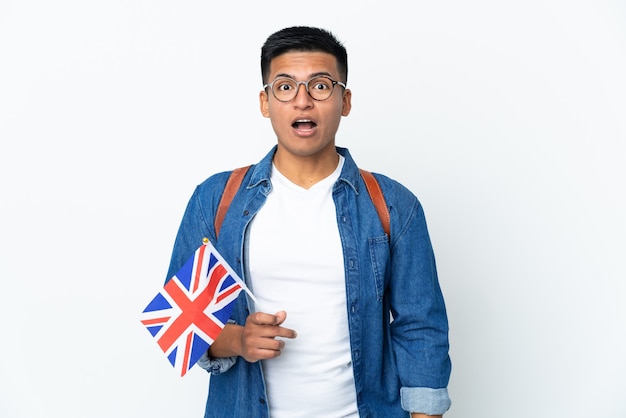 Jovem equatoriana segurando uma bandeira do Reino Unido, isolada no fundo branco, com expressão facial de surpresa