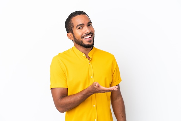 Jovem equatoriano isolado no fundo branco apresentando uma ideia enquanto olha sorrindo para