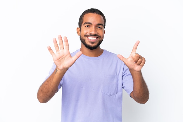 Jovem equatoriano isolado no fundo branco contando sete com os dedos