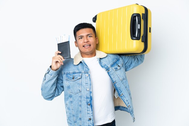 Jovem equatoriano isolado no fundo branco de férias com mala e passaporte