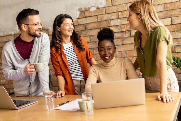 Jovem equipa multiétnica a trabalhar ao lado da parede de tijolos num escritório de estilo industrial