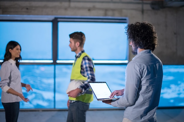 jovem equipe de empresários em grupo, arquiteto e engenheiro no canteiro de obras, verificando documentos e fluxo de trabalho de negócios usando computador portátil no novo escritório de inicialização