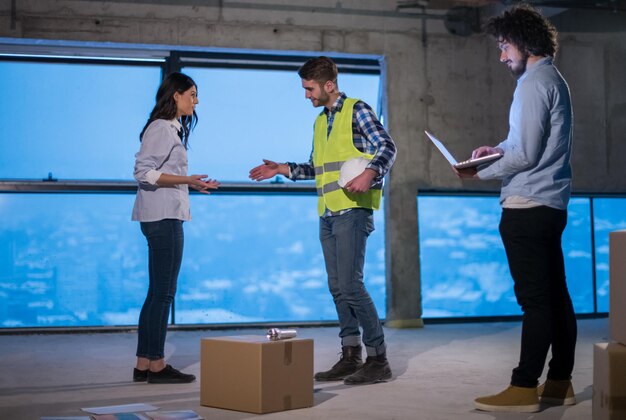 jovem equipe de empresários em grupo, arquiteto e engenheiro no canteiro de obras, verificando documentos e fluxo de trabalho de negócios usando computador portátil no novo escritório de inicialização