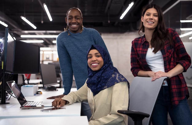 jovem equipe multiétnica de desenvolvedores de software trabalhando juntos usando um laptop enquanto escrevem código de programação em um escritório moderno