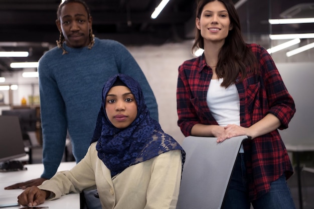 jovem equipe multiétnica de desenvolvedores de software trabalhando juntos usando um laptop enquanto escrevem código de programação em um escritório moderno