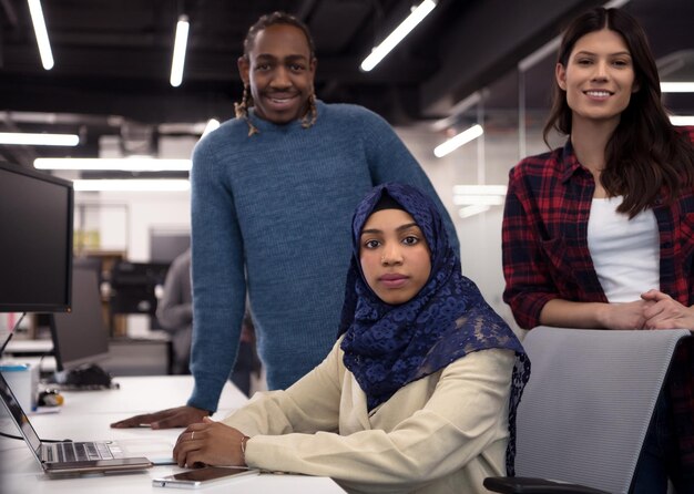 jovem equipe multiétnica de desenvolvedores de software trabalhando juntos usando um laptop enquanto escrevem código de programação em um escritório moderno