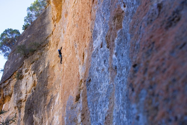 Foto jovem escalando grande parede de pedra na montanha