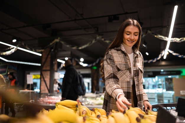 Jovem escolhe bananas na seção de frutas