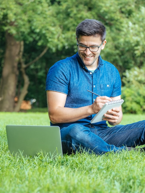 Jovem, escrevendo em seu caderno no parque da cidade