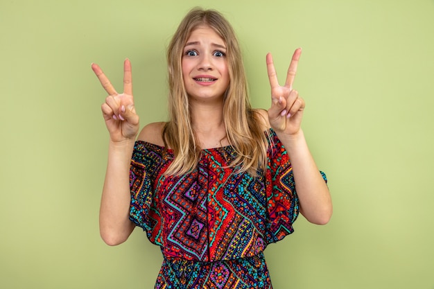 Foto jovem eslava loira ansiosa gesticulando sinal de vitória olhando para frente