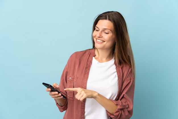 Jovem eslovaca isolada em um fundo azul enviando uma mensagem ou e-mail com o celular