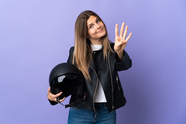 Jovem eslovaca segurando um capacete de motociclista isolado na parede roxa feliz e contando quatro com os dedos