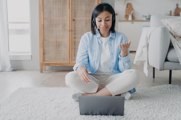 Jovem espanhola em fone de ouvido com microfone tem videoconferência e streaming de vídeo