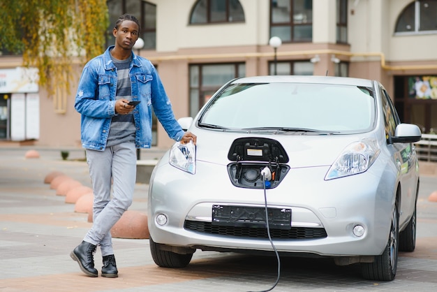 Jovem esperando seu carro elétrico ser carregado