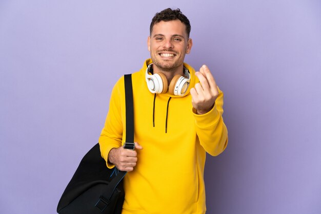 Jovem esporte caucasiano homem com bolsa isolada fazendo gesto de dinheiro