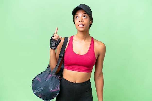 Jovem esporte mulher afro-americana com bolsa esportiva sobre fundo isolado apontando para cima e surpreso