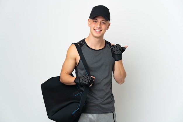 Jovem esportista caucasiano com bolsa isolada no fundo branco apontando para o lado para apresentar um produto