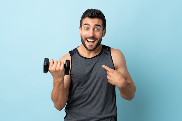 Jovem esportista com barba fazendo levantamento de peso com expressão facial surpresa