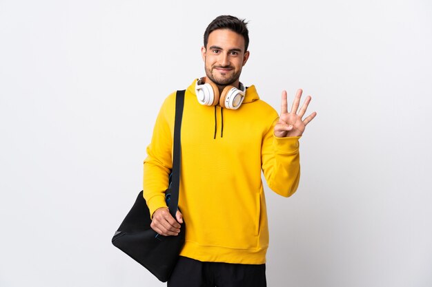 Jovem esportista com bolsa esporte isolada no fundo branco feliz e contando quatro com os dedos