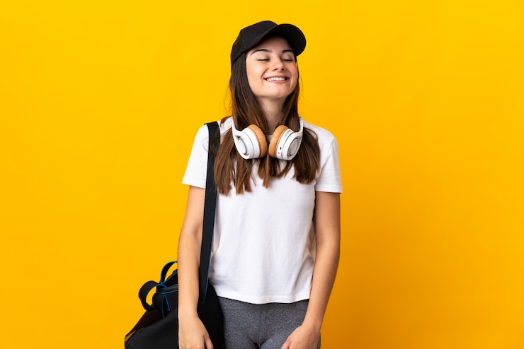 Foto jovem esportista com bolsa esportiva isolada em amarelo rindo