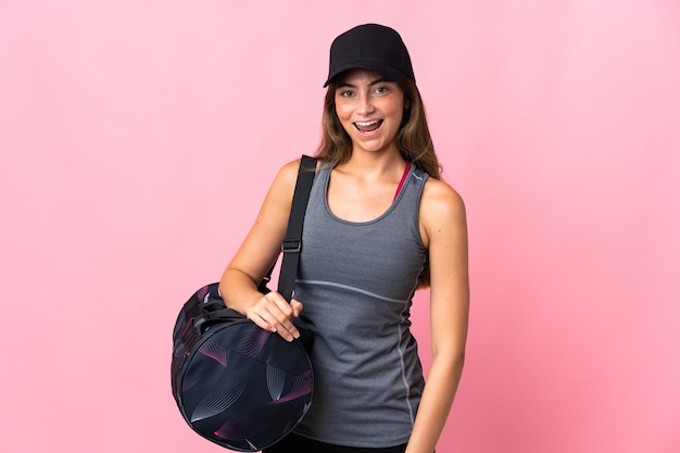 Jovem esportista com bolsa esportiva isolada em rosa com expressão facial surpresa